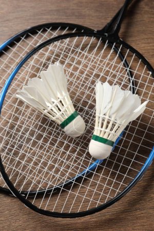 Photo for Feather badminton shuttlecocks and rackets on wooden table, top view - Royalty Free Image
