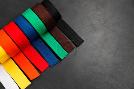 Cinturones de karate de colores sobre fondo gris, planas. Espacio para texto