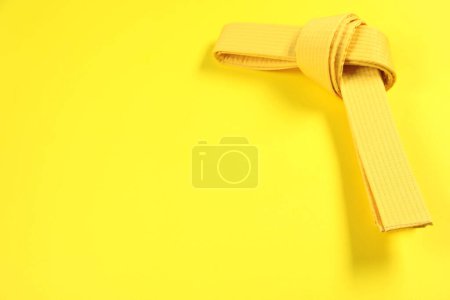 Cinturón de karate sobre fondo amarillo, espacio para texto