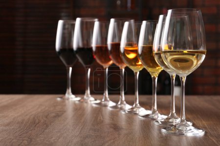 Photo for Different tasty wines in glasses on wooden table - Royalty Free Image