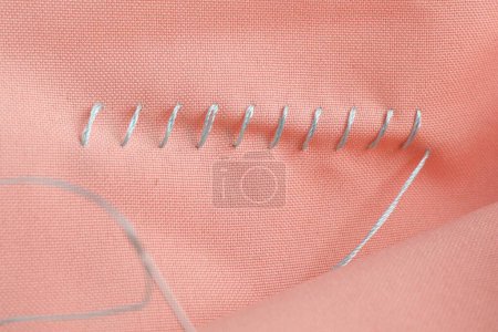 Téléchargez les photos : Fil à coudre et points de suture sur tissu corail, vue de dessus - en image libre de droit