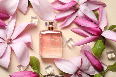 Téléchargez les photos : Belles fleurs de magnolia rose, bouteille de parfum et glaçons sur fond beige, plat - en image libre de droit