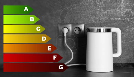 Foto de Energy efficiency rating label and electric kettle on grey table - Imagen libre de derechos
