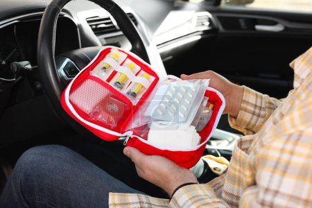 Téléchargez les photos : Homme tenant une trousse de premiers soins avec des médicaments à l'intérieur de la voiture, gros plan - en image libre de droit