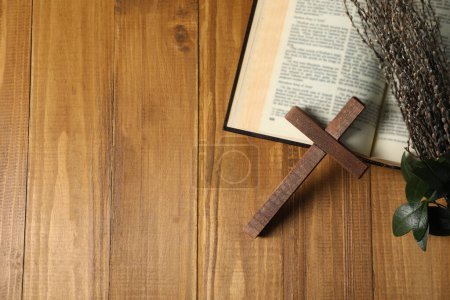 Kreuz, Bibel und Weidenzweige auf Holztisch, flach gelegt. Raum für Text