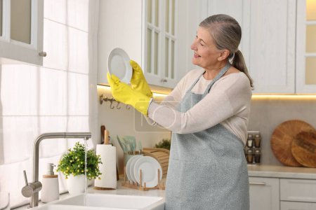 Téléchargez les photos : Bonne plaque de lavage de femme au foyer dans l'évier de cuisine - en image libre de droit