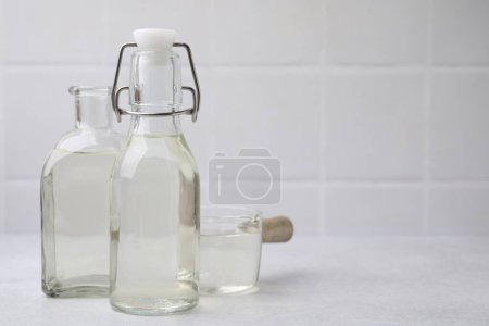 Foto de Vinagre en botellas de vidrio y cacerola sobre mesa ligera, espacio para texto - Imagen libre de derechos