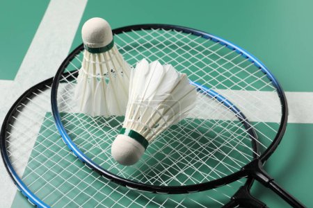 Photo for Feather badminton shuttlecocks and rackets on green table, closeup - Royalty Free Image