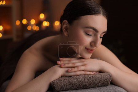 Téléchargez les photos : Thérapie spa. Belle jeune femme allongée sur une table de massage dans le salon - en image libre de droit