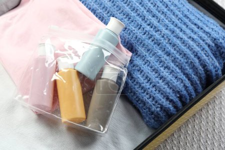 Plastic bag of cosmetic travel kit in suitcase, top view