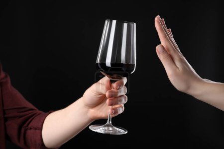 Alcohol addiction. Woman refusing glass of wine on black background, closeup