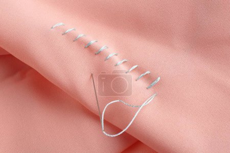 Téléchargez les photos : Aiguille à coudre avec fil et points de suture sur tissu corail, gros plan - en image libre de droit