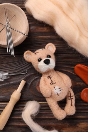 Téléchargez les photos : Ours feutré, laine et outils sur table en bois, pose plate - en image libre de droit