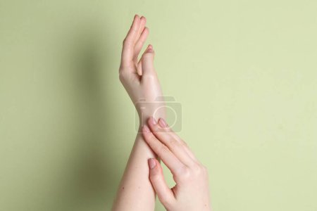 Téléchargez les photos : Femme appliquant de la crème sur sa main sur fond vert, gros plan - en image libre de droit
