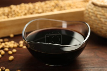 Soy sauce in bowl on wooden table, closeup