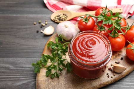 Photo for Tasty ketchup, fresh tomatoes, parsley and spices on grey wooden table, space for text - Royalty Free Image