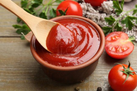 Photo for Bowl and spoon with tasty ketchup, fresh tomatoes, parsley and spices on wooden table - Royalty Free Image