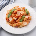 Tasty pasta with tomato sauce, cheese and basil on white table