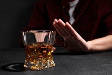 Téléchargez les photos : L'alcoolisme. Femme refusant un verre de whisky à la table sombre texturée, gros plan - en image libre de droit
