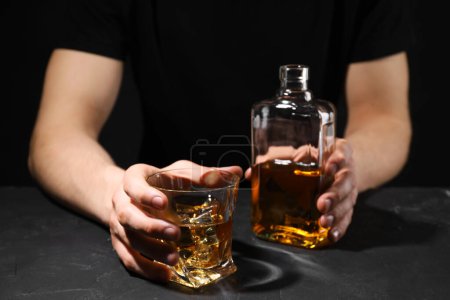 Téléchargez les photos : L'alcoolisme. Homme avec whisky à la table sombre texturée, mise au point sélective - en image libre de droit