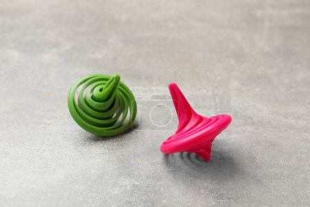 Bright spinning tops on grey textured background, closeup