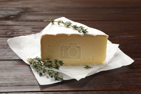 Téléchargez les photos : Pièce de fromage camembert savoureux et thym sur table en bois, gros plan - en image libre de droit