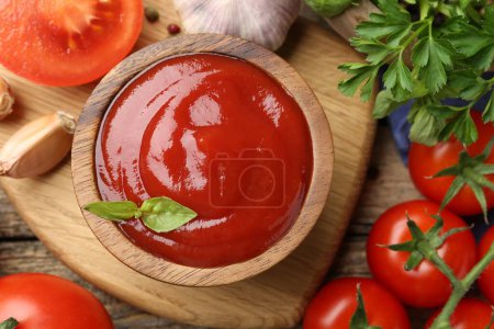 Photo for Tasty ketchup, fresh tomatoes, parsley and spices on wooden table, flat lay - Royalty Free Image