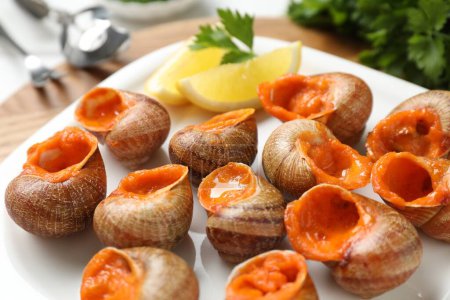 Téléchargez les photos : Délicieux escargots cuits avec du citron et du persil sur la table, gros plan - en image libre de droit