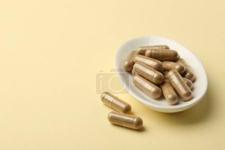 Téléchargez les photos : Capsules vitaminées sur fond jaune pâle, espace pour le texte - en image libre de droit