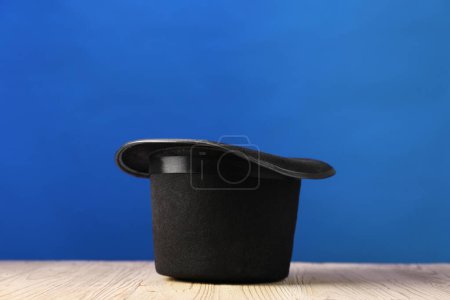 Magician's hat on wooden table against blue background