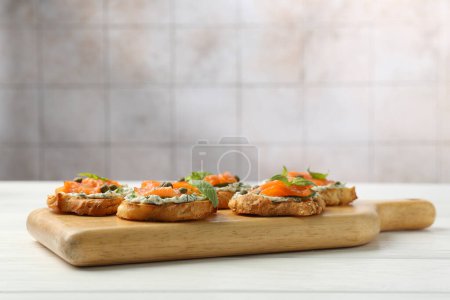 Téléchargez les photos : Canapés savoureux avec saumon, câpres et sauce sur table en bois blanc, espace pour le texte - en image libre de droit