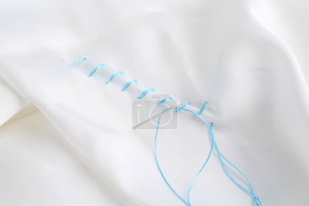 Téléchargez les photos : Aiguille à coudre avec fil et points de suture sur tissu blanc, gros plan - en image libre de droit