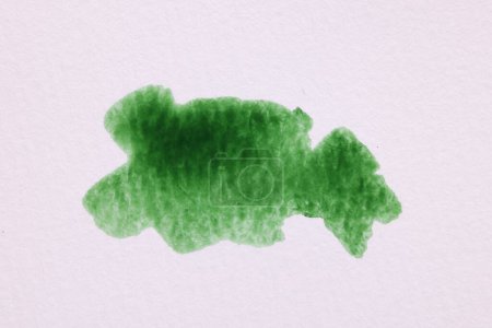 Blot of green watercolor paint on white paper, top view