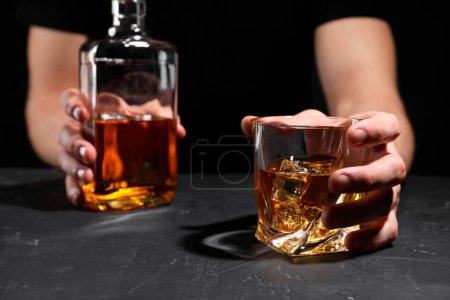 Adicción al alcohol. Hombre con whisky en la mesa de textura oscura, enfoque selectivo