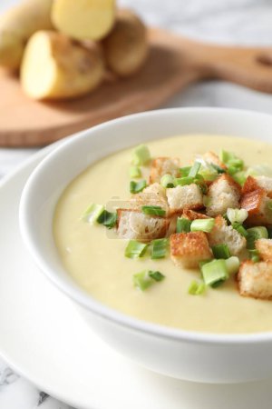 Téléchargez les photos : Soupe de pommes de terre savoureuse avec croûtons et oignon vert dans un bol sur une table blanche, gros plan - en image libre de droit