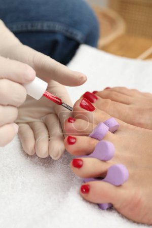 Foto de Pedicura pintar las uñas de los pies del cliente con esmalte rojo en el salón de belleza, primer plano - Imagen libre de derechos