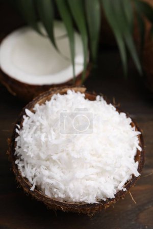 Photo for Coconut flakes in nut shell on wooden table - Royalty Free Image