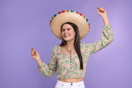 Mujer joven en sombrero mexicano bailando sobre fondo violeta