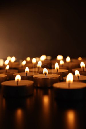 Burning candles on surface in darkness, closeup