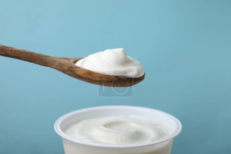 Comer delicioso yogur natural sobre fondo azul claro