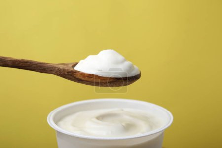 Comer delicioso yogur natural sobre fondo amarillo
