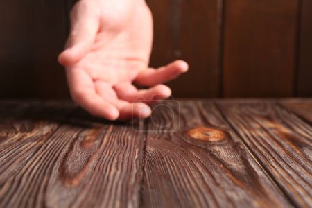 Man holding hand above wooden table, selective focus. Space for text