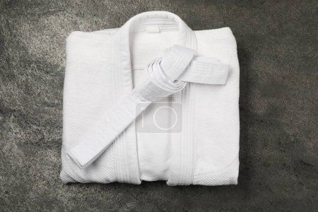 Photo for White karate belt and kimono on gray textured background, top view - Royalty Free Image