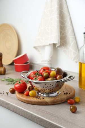 Colador de metal con tomates en la encimera en la cocina