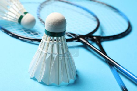 Photo for Feather badminton shuttlecocks and rackets on light blue background, closeup - Royalty Free Image