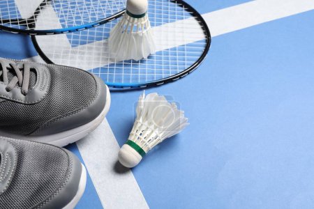 Photo for Feather badminton shuttlecocks, rackets and sneakers on court, space for text - Royalty Free Image