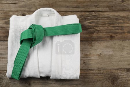 Téléchargez les photos : Ceinture de karaté verte et kimono blanc sur fond bois, vue de dessus. Espace pour le texte - en image libre de droit