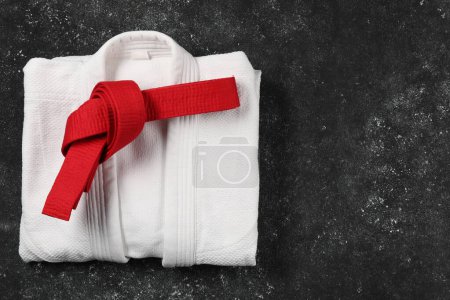 Photo for Red karate belt and white kimono on gray textured background, top view. Space for text - Royalty Free Image
