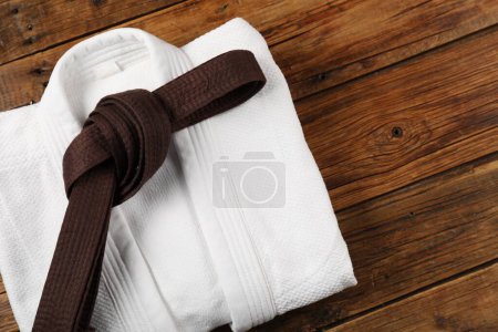 Photo for Brown karate belt and white kimono on wooden background, top view - Royalty Free Image