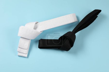 Photo for White and black karate belts on light blue background, flat lay - Royalty Free Image